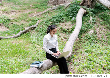 Young Professional Woman Working on Laptop Outdoors in a Natural Setting, Embracing Remote Work and Nature Young Professional Woman Working on Laptop Outdoors in a Natural Setting, Embracing Remote Work and Nature 128369171