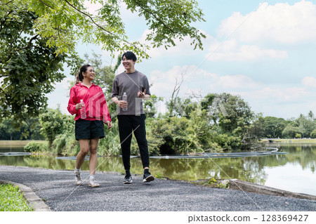 Young Couple Enjoying a Refreshing Jog in the Park on a Sunny Day Young Couple Enjoying a Refreshing Jog in the Park on a Sunny Day 128369427