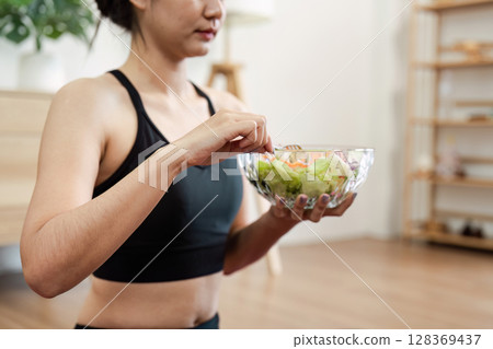 Woman Enjoying a Healthy Salad at Home in a Modern Living Room Setting Promoting Wellness and Healthy Lifestyle 128369437