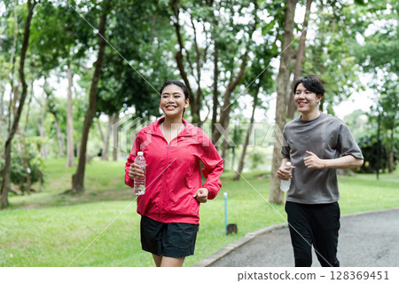 Young Couple Jogging in a Park on a Sunny Day, Staying Fit and Healthy with Smiles and Water Bottles Young Couple Jogging in a Park on a Sunny Day, Staying Fit and Healthy with Smiles and Water Bottles 128369451