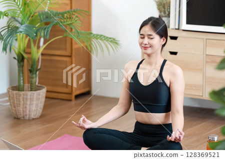 Young Woman Practicing Yoga at Home for Wellness and Relaxation in a Modern Living Room Setting 128369521