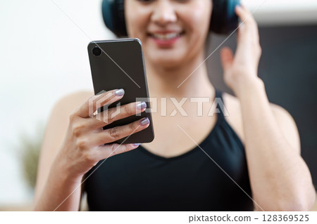 Young Woman Engaging in Wellness Activity with Smartphone and Headphones, Promoting Healthy Lifestyle and Mental Wellbeing 128369525
