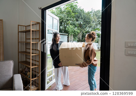 Happy Lesbian Couple Moving into New Home Together, Carrying Boxes and Smiling, Embracing New Beginnings and Fresh Start 128369599