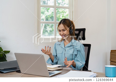 Young Professional Woman Working from Home on Laptop with Headset, Engaged in Virtual Meeting in Bright Modern Home Office 128369644