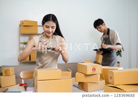 Young Entrepreneurs Managing Online Small Business with Packaging and Inventory in Home Office 128369688