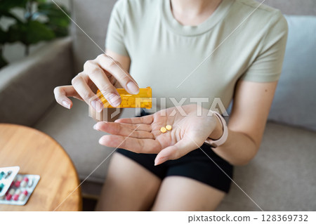 Woman Taking Medication at Home - Healthcare and Wellness Concept with Pills and Prescription Bottle 128369732