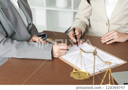 Professional Lawyers Discussing Legal Documents in Office with Scales of Justice on Desk Professional Lawyers Discussing Legal Documents in Office with Scales of Justice on Desk 128369747