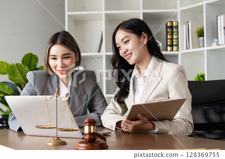 Professional Lawyers Discussing Legal Matters in Modern Office with Scales of Justice and Gavel on Desk 128369755