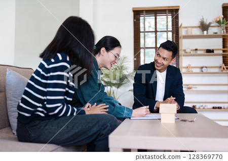 Real Estate Agent Assisting lgbt lesbian Couple client with Signing Contract for New Home Purchase in Modern Living Room Setting Real Estate Agent Assisting lgbt lesbian Couple client with Signing Contract for New Home Purchase in Modern Living Room Setting 128369770