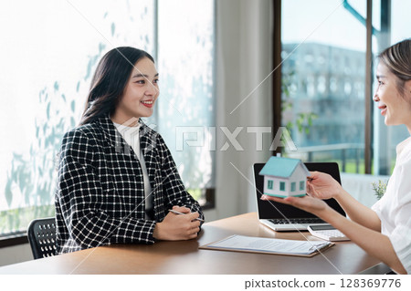 Professional Real Estate Agent Discussing Property Sale with Client in Modern Office Setting 128369776
