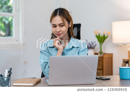 Young Professional Woman Working Remotely from Home Office with Laptop and Notepad Young Professional Woman Working Remotely from Home Office with Laptop and Notepad 128369938