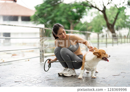 Wellness and Pet Care. Young woman enjoying time with her corgi dog in a park. Wellness and Pet Care. Young woman enjoying time with her corgi dog in a park. 128369996