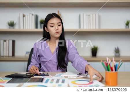Graphic Design and Color Selection. A designer organizing color samples while working at a desk. Graphic Design and Color Selection. A designer organizing color samples while working at a desk. 128370003