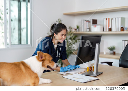 Veterinary Care and Technology. A veterinarian examining a patient's records on a computer while a dog observes. 128370005