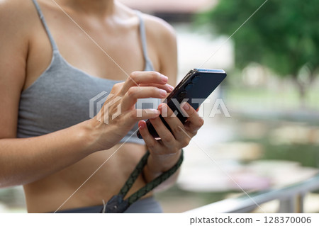Wellness and Technology. Close-up of woman using smartphone while exercising outdoors. 128370006