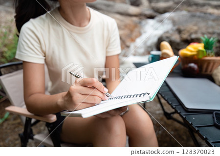 Creativity and Nature. Young woman writing in a notebook outdoors. Creativity and Nature. Young woman writing in a notebook outdoors. 128370023