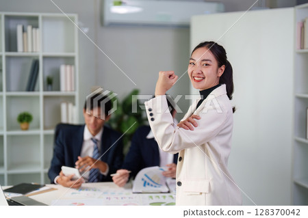 Empowered Businesswoman Celebrating Success. Confident professional showing determination in office. Empowered Businesswoman Celebrating Success. Confident professional showing determination in office. 128370042