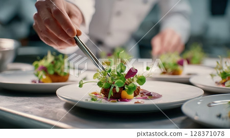 First-person view of plating fine dining dish with tweezers and microgreens 128371078