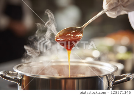 Chef Tasting Sauce with Silver Spoon Over Simmering Pot 128371346