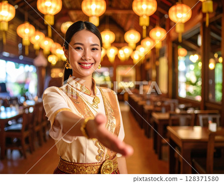AI generated image of a Thai waiter in traditional uniform gesturing to invite diners into a vibrant Thai restaurant. 128371580