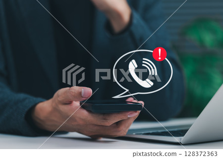 Phone Scam Alert and Warning Notification Concept. A person holding smartphone displaying call icon with alert symbol, representing scam call warnings, fraud awareness, digital communication threats, 128372363
