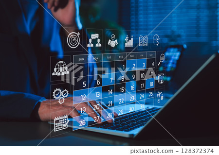 Time management and calendar planning concept. A person using laptop with digital monthly calendar, representing time management, event planning, appointment, agenda meeting, and schedule organization 128372374