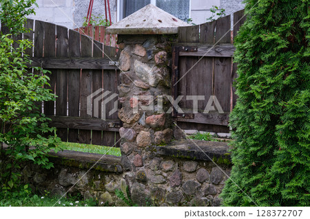 Stone wall and wooden gate enhance tranquil garden setting in rural area during daytime Stone wall and wooden gate enhance tranquil garden setting in rural area during daytime 128372707