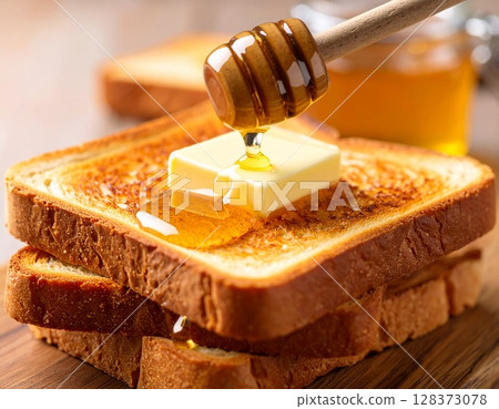 將奶油和蜂蜜塗在烤好的麵包上。 128373078