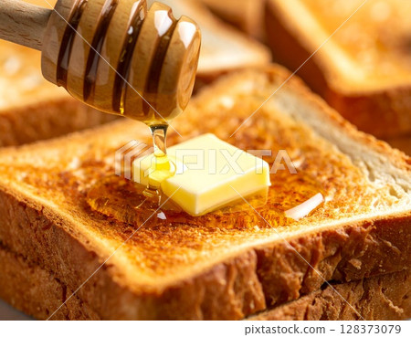 將奶油和蜂蜜塗在烤好的麵包上。 128373079