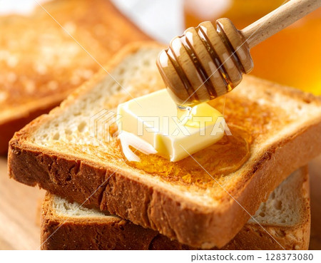 將奶油和蜂蜜塗在烤好的麵包上。 128373080
