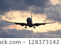 A passenger plane approaching an airport at dusk 128373142