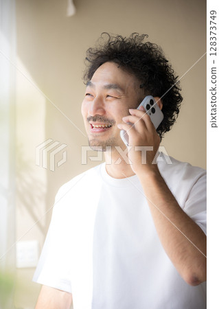 一位留著鬍鬚的男子在明亮的陽光下用智慧型手機聊天 128373749