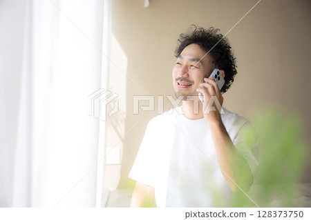 一位留著鬍鬚的男子在明亮的陽光下用智慧型手機聊天 128373750