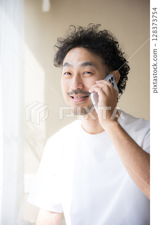 一位留著鬍鬚的男子在明亮的陽光下用智慧型手機聊天 一位留著鬍鬚的男子在明亮的陽光下用智慧型手機聊天 128373754