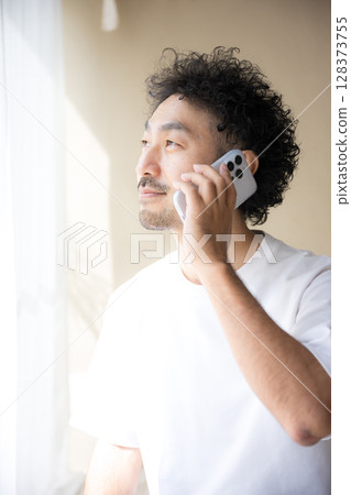一位留著鬍鬚的男子在明亮的陽光下用智慧型手機交談的側面像 一位留著鬍鬚的男子在明亮的陽光下用智慧型手機交談的側面像 128373755
