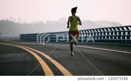 Asian fitness woman runner running on seaside bridge Asian fitness woman runner running on seaside bridge 128375586