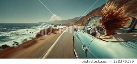 Vintage convertible car driving along coastal highway with ocean views stretching to horizon and wind blown hair creating 128376159