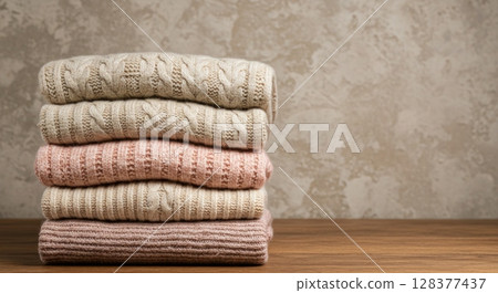 Cozy knitwear stack on wooden surface against textured background - autumn winter fashion Cozy knitwear stack on wooden surface against textured background - autumn winter fashion 128377437