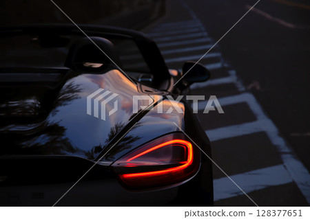 A black convertible with the morning glow reflected on its body 128377651