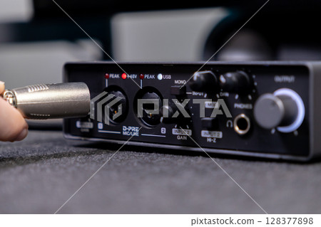 Hand connecting a durable XLR cable into a compact audio interface, showcasing D-PRE MICLINE, 48V power, and USB for high-quality home studio recording Hand connecting a durable XLR cable into a compact audio interface, showcasing D-PRE MICLINE, 48V power, and USB for high-quality home studio recording 128377898