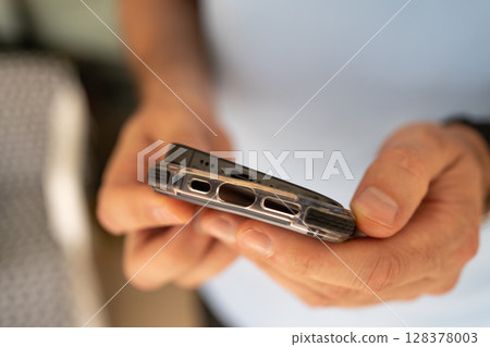 Close-up of a man putting on a protective shockproof case on his phone. Close-up of a man putting on a protective shockproof case on his phone. 128378003