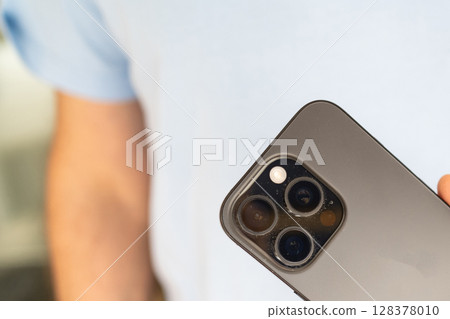 Dust on a phone camera close-up. A man holds a smartphone in his hands. 128378010