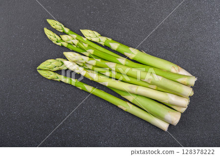 Pile of fresh raw green asparagus or sparrowgrass stems on black textured background Pile of fresh raw green asparagus or sparrowgrass stems on black textured background 128378222