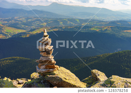 Stacked rock cairn on mountain peak with Carpathian view background. Travel and hiking exploration 128378258