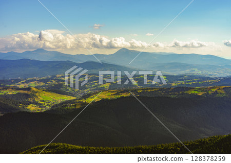 Cloudy horizon over layers of Carpathian mountain ridges in summer light. Aerial view landscape 128378259