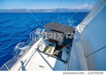 View from the mast down to the cockpit of a sailing yacht moving under full sails near Croatia. Sailing lifestyle, freedom, teamwork and adventure at sea. 128379284