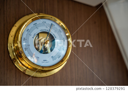 Classic barometer mounted on a wooden wall inside a sailing yacht near Croatia. Nautical equipment, interior detail and traditional life at sea. 128379291