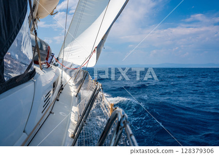 Side of a sailing yacht cutting through the sea with full sails near Croatia. Motion, freedom, sailing lifestyle and adventure on the open water. Side of a sailing yacht cutting through the sea with full sails near Croatia. Motion, freedom, sailing lifestyle and adventure on the open water. 128379306