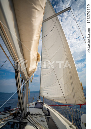 Full white sails blown by the wind against blue sky during sailing near Croatia. Symbol of movement, freedom and summer maritime journey. Full white sails blown by the wind against blue sky during sailing near Croatia. Symbol of movement, freedom and summer maritime journey. 128379329