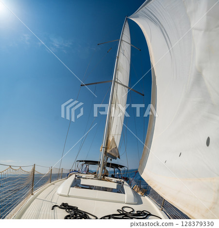 White sails filled with wind, seen from the bow of a sailing yacht near Croatia. Freedom, clean energy, adventure and mindful travel on the open sea. White sails filled with wind, seen from the bow of a sailing yacht near Croatia. Freedom, clean energy, adventure and mindful travel on the open sea. 128379330